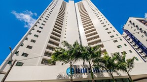 A high-rise building with multiple floors, a clear blue sky, and palm trees in the foreground. - Studio in Condo. w/ Pool and City View Bcm0403 (Recife)