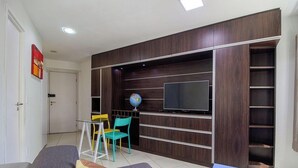 A modern living room with a flat-screen TV, a globe, and a bookshelf. - Studio in Condo. w/ Pool and City View Bcm0403 (Recife)