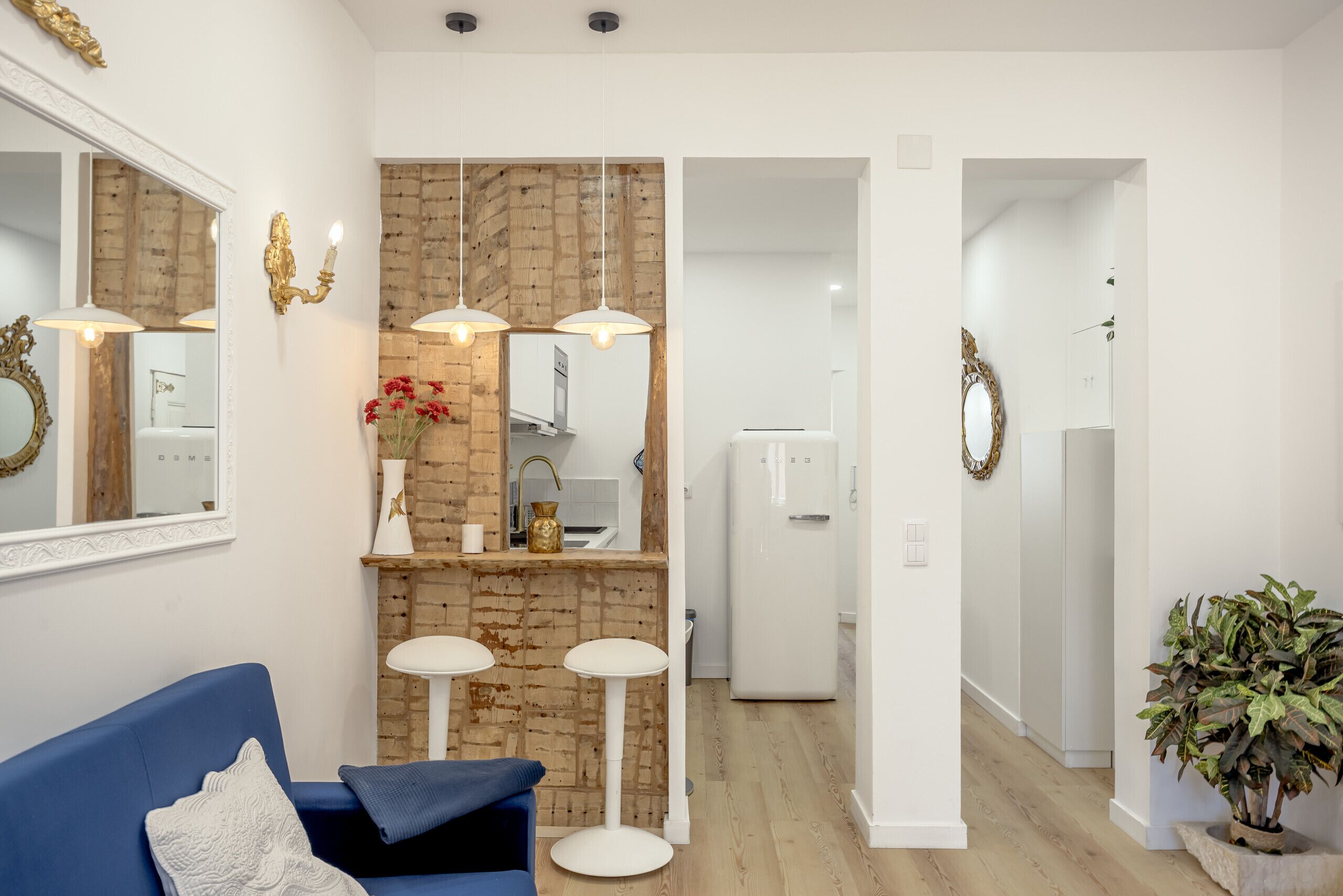 Una sala de estar moderna con un sofá azul, dos lámparas de pie y un espejo decorativo.