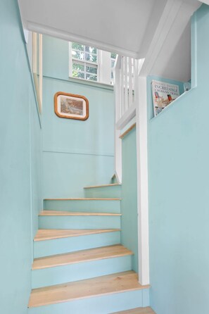 A staircase with light blue walls and wooden steps. - Charming Lakeside Village Farmhouse Retreat (Harrison)