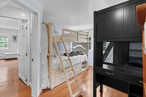A room with a bunk bed, a wooden ladder, a black TV stand, and a white door. - Charming Lakeside Village Farmhouse Retreat (Harrison)