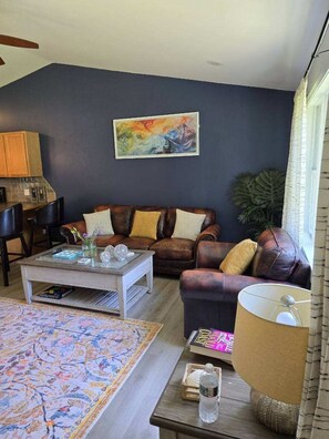A living room with a sofa, coffee table, and a painting on the wall. - Private 2BR Bungalow • Deck & Grill • Near Newport & RI Coastline  (North Kingstown)