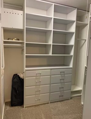 Ein begehbarer Kleiderschrank mit mehreren Regalen und Schubladen.