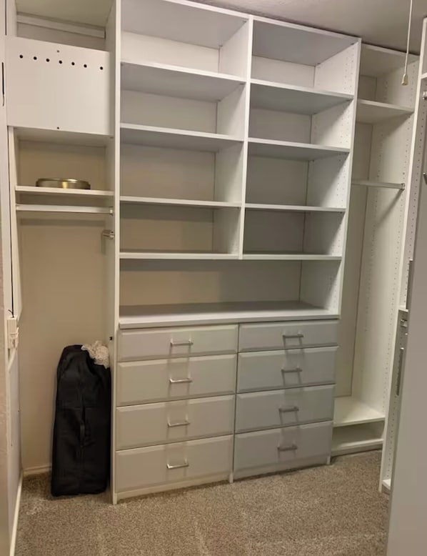 Ein begehbarer Kleiderschrank mit mehreren Regalen und Schubladen.