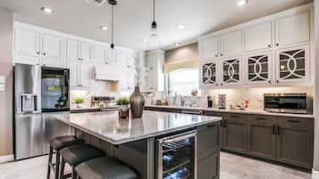 A modern kitchen with a central island, stainless steel appliances, and white cabinetry.