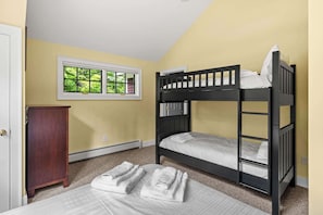 A child's bedroom with bunk beds, a window with a view of trees, a wooden dresser, and a radiator. - Luxury Okemo Lodge | 0.5 Mi to Slopes | Sleeps 14 (Ludlow)