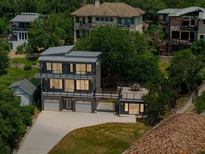 Ein modernes, zweistöckiges Haus mit Garage, umgeben von üppigem Grün und weiteren Wohngebäuden.
