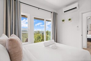 A bedroom with a large bed, two windows, and a view of the outdoors. - Hilltop Home + Guest Casita w Sweeping Lake Travis Views from Your Rooftop Deck (Austin)