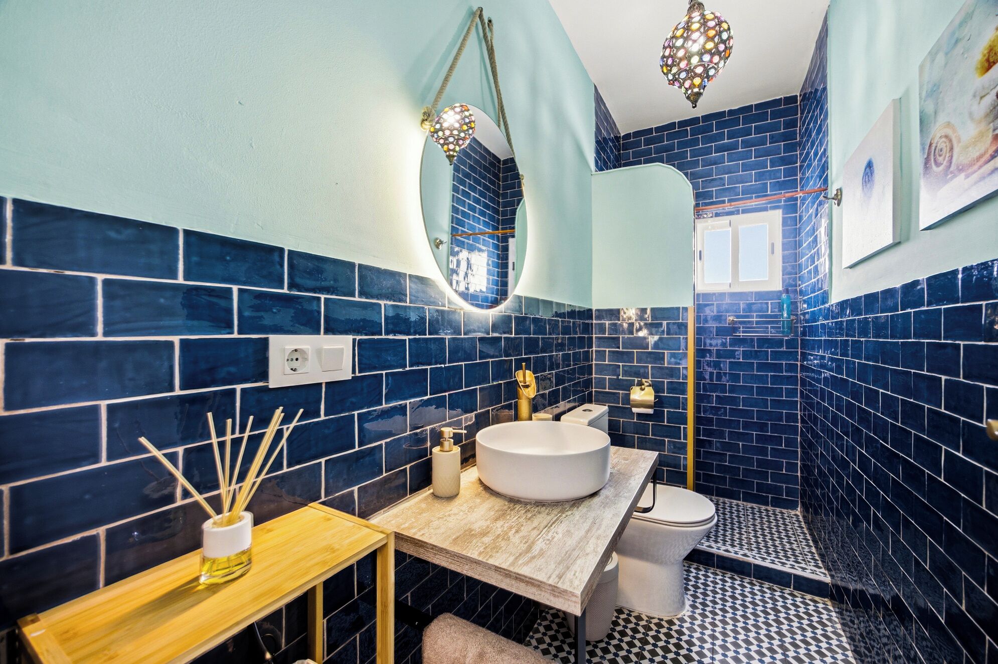 A bathroom with a round sink, a toilet, and a shower area.