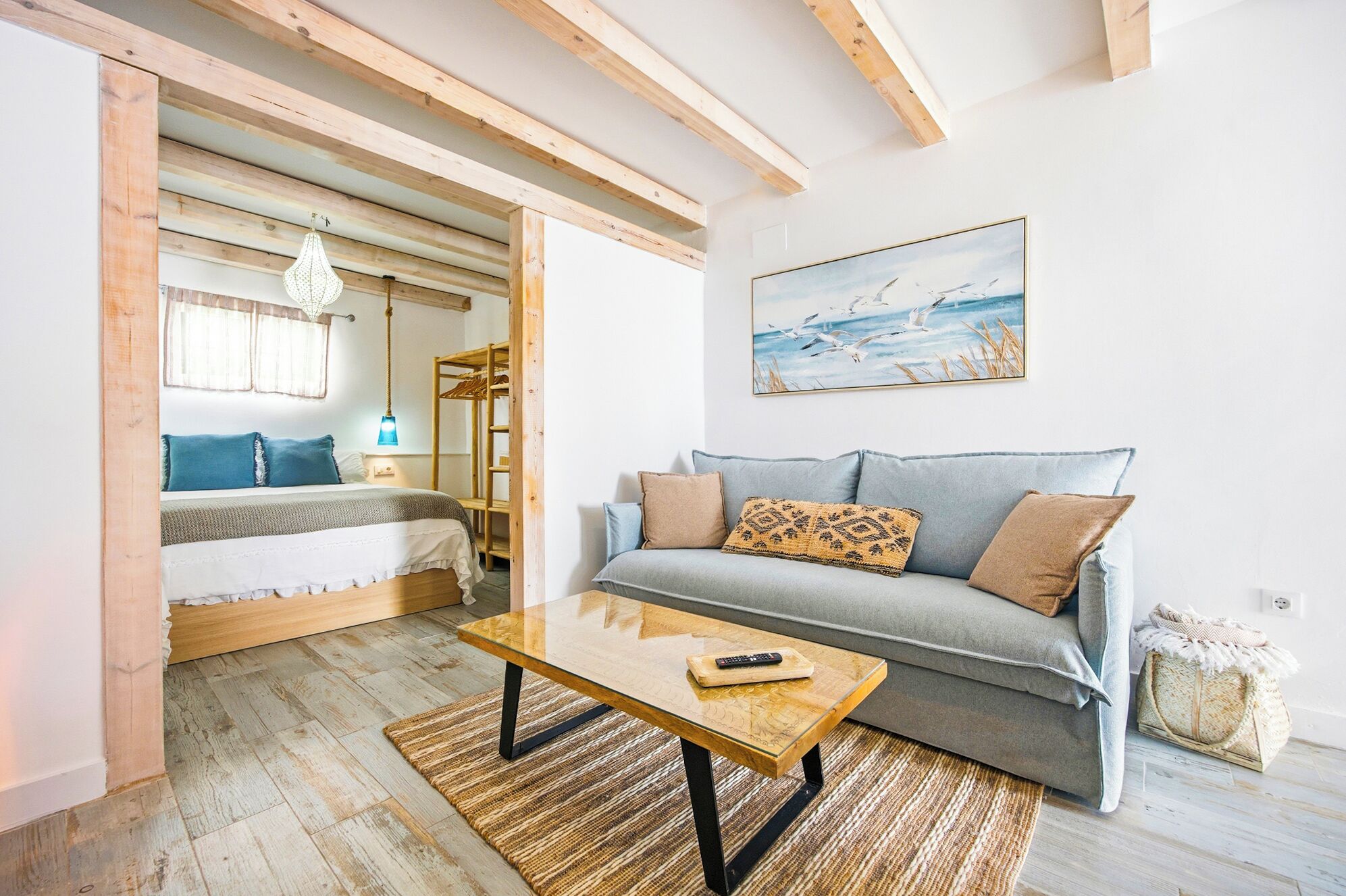 A cozy room with a bed, a sofa, a wooden coffee table, and a painting on the wall.