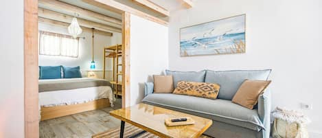A cozy room with a bed, a sofa, a wooden coffee table, and a painting on the wall.