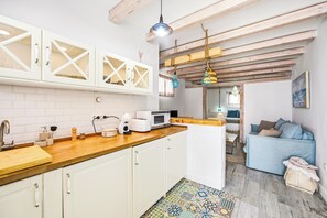 A kitchen with white cabinets, a wooden countertop, a microwave, and a coffee machine. - Charming Apartment in Vejer de la Frontera (Vejer de la Frontera)