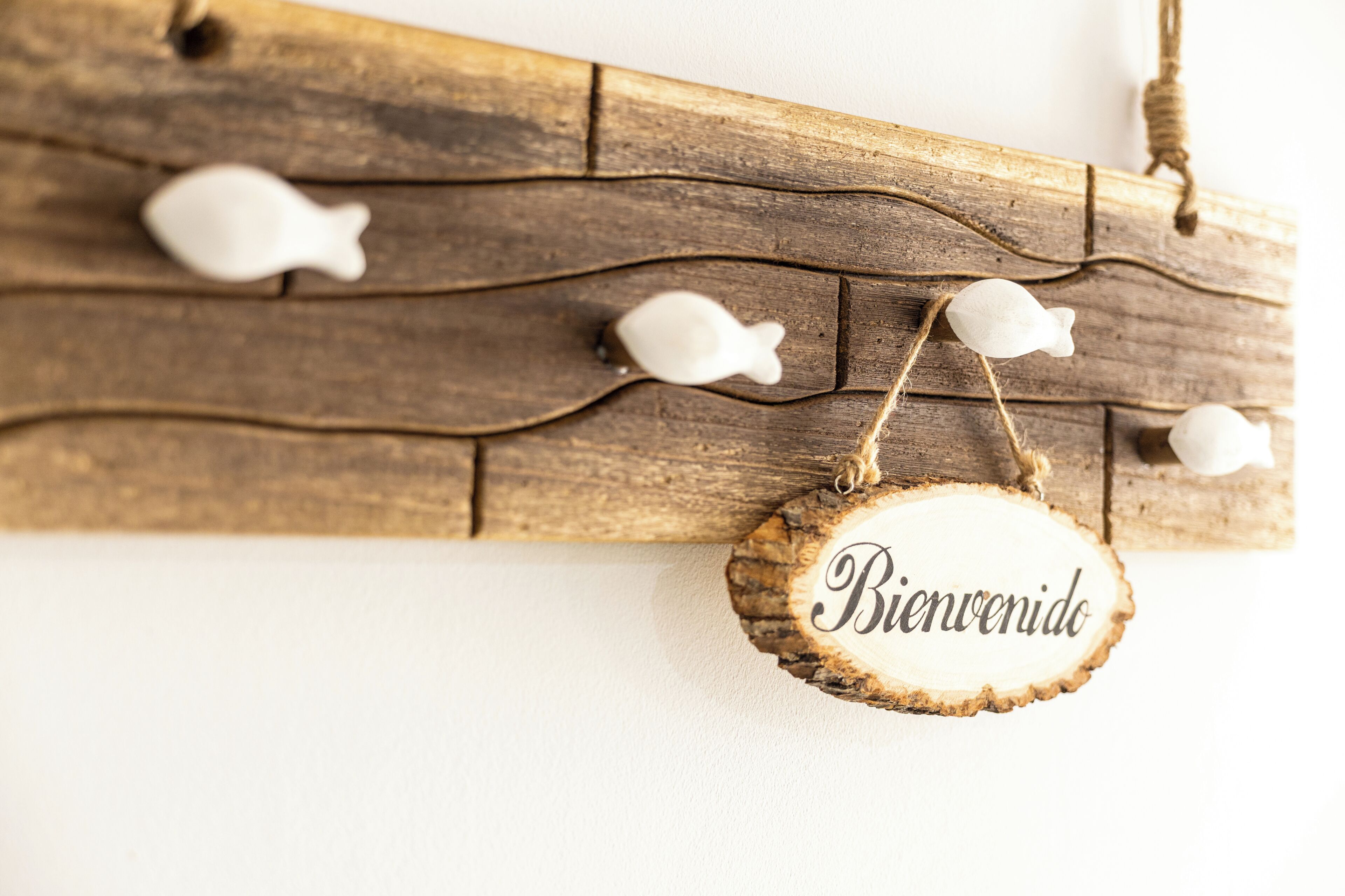 A wooden wall with a rustic fish decoration and a welcome sign.