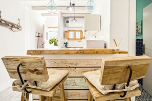 A rustic wooden dining table with two chairs, a kitchen area with wooden cabinets, and pendant lighting. - Charming Apartment in Vejer de la Frontera (Vejer de la Frontera)