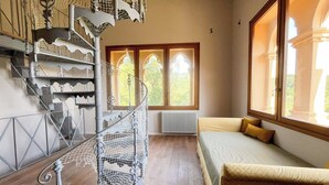 Een kamer met een wenteltrap, een bed en grote ramen.