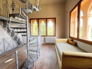 Ein Zimmer mit Wendeltreppe, einem Bett und großen Fenstern.