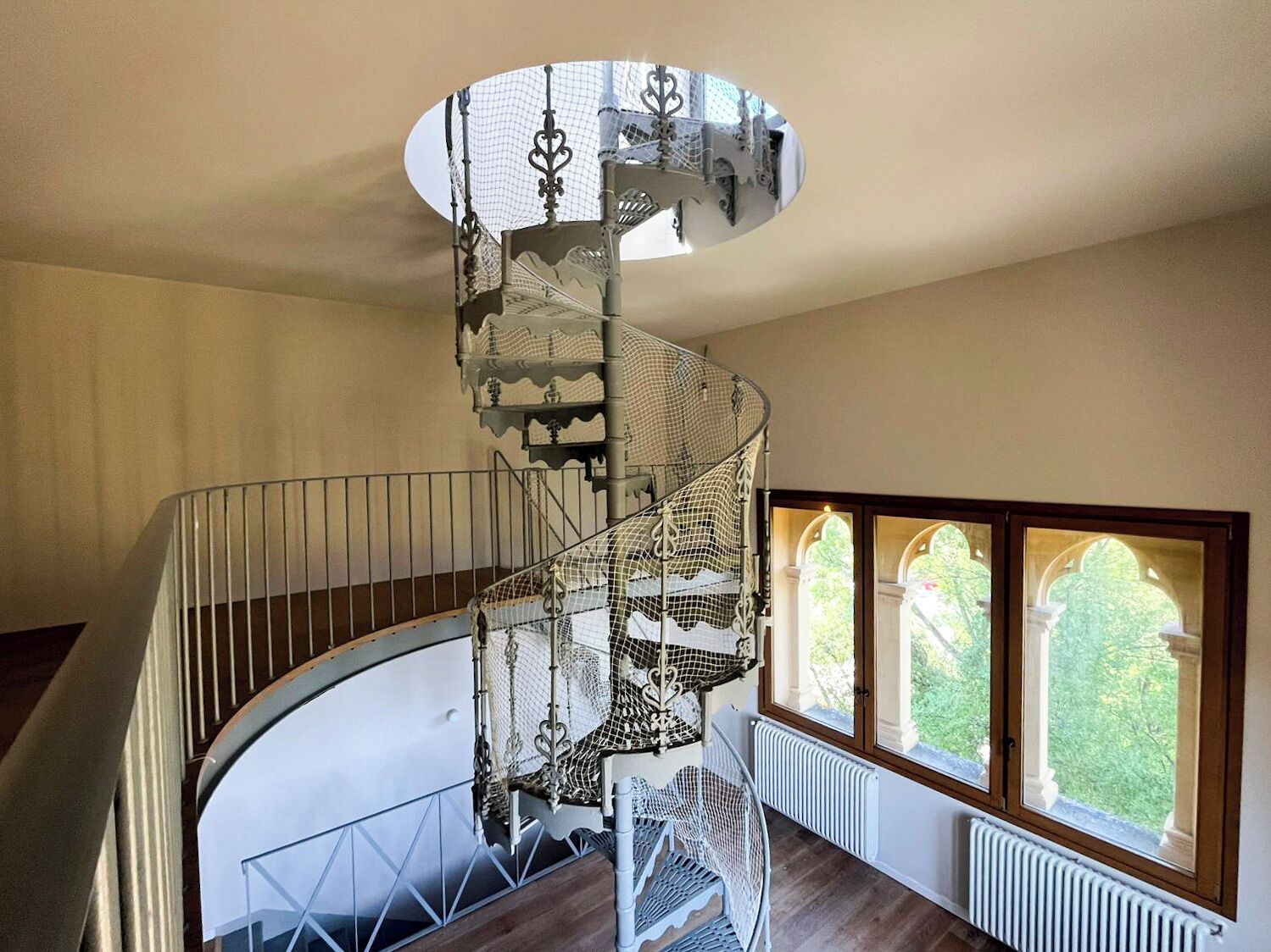 Eine Wendeltreppe mit aufwendiger Metallgeländerung und einer weißen Wand.