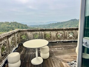 A balcony with a round table and four stools, overlooking a scenic landscape with hills and trees. - La Casa Torre – Historic Tuscan Tower with Pool (Pistoia)