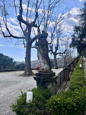 A statue on a pedestal with a gravel path and a fence. - La Casa Torre – Historic Tuscan Tower with Pool (Pistoia)