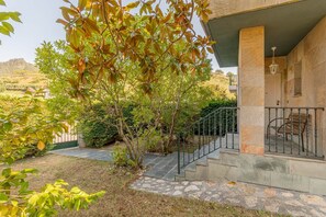 A building with a stone facade, a staircase with a metal railing, and a view of a hilly landscape. - Zeharbide - baskeyrentals (Erribera)
