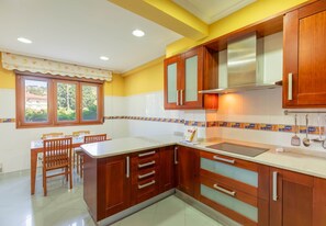 A kitchen with wooden cabinets, a white countertop, and a window with a view of greenery. - Zeharbide - baskeyrentals (Erribera)
