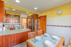 A kitchen with wooden cabinets, a built-in oven, and a dining area with a table set for four.