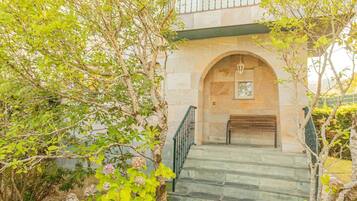 A stone staircase leading to a building entrance with a metal railing and a bench.