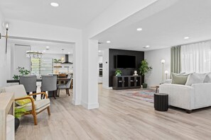 A modern living room with a sofa, chairs, a dining area, and a kitchen in the background. - Intracoastal Waterfront Villa w/ Private Pool (Pompano Beach)