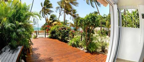 A wooden deck with a view of palm trees and a beach.