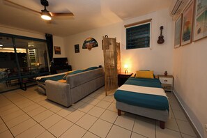 Una habitación con dos camas, un sofá, una mesa de comedor y un ventanal con vistas.