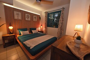 Ein Schlafzimmer mit Bett, Nachttischen, einem Fenster und einem Deckenventilator.