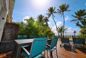 Une terrasse extérieure avec un plancher en bois, des chaises et des tables en métal.