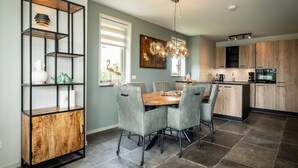 Una cucina moderna con zona pranzo, che include un armadietto in legno, un lampadario e un tavolo da pranzo con sedie.