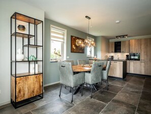 A modern kitchen with a dining area, featuring a wooden cabinet, a chandelier, and a dining table with chairs. - Pet-free Country House With Sauna (De Koog)
