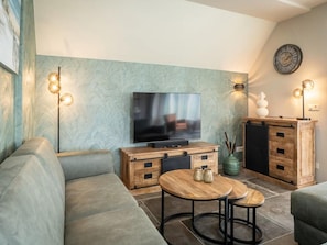 A modern living room with a flat-screen TV, wooden furniture, and decorative lighting. - Pet-free Country House With Sauna (De Koog)