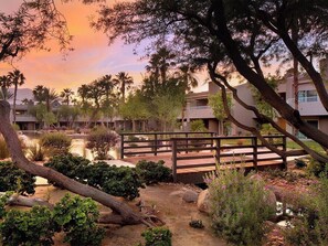 A resort with a wooden bridge over a water feature, surrounded by lush greenery and palm trees. - 2 Bedroom Villa at Westin Mission Hills Resort (Rancho Mirage)