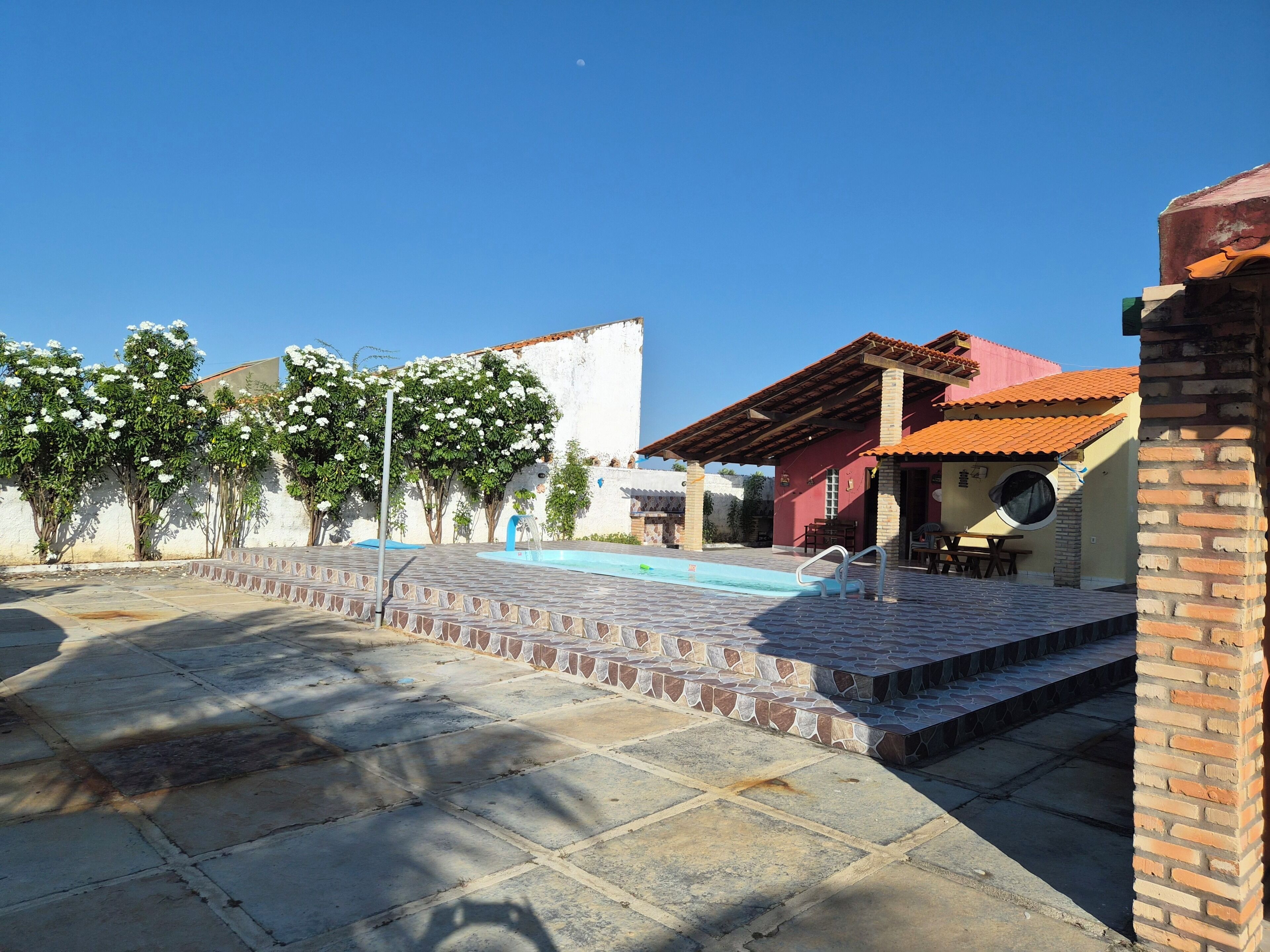 Ein Innenhof mit Swimmingpool, einer überdachten Sitzgelegenheit und einem Gebäude mit rotem Dach.