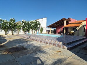 A courtyard with a swimming pool, outdoor seating, and a building with a red roof. - 2-bedroom and 4-suits house in beautiful Luís Correia with cool ocean breeze (Luís Correia)