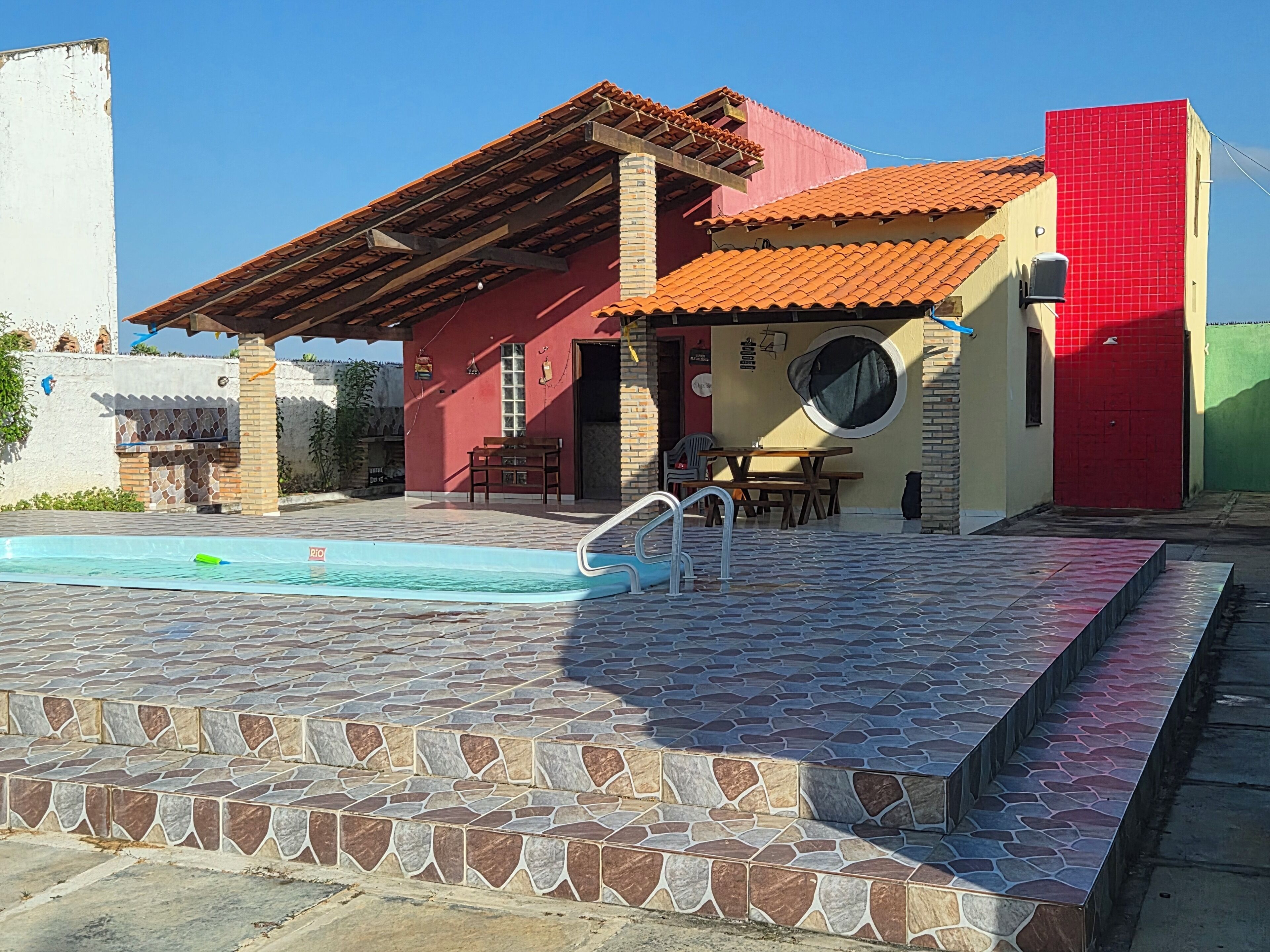 Une maison avec une piscine, un patio et un espace extérieur aménagé pour s’asseoir.