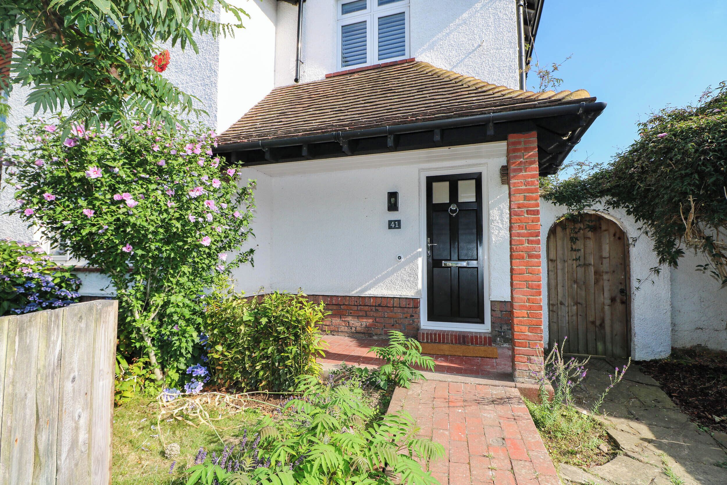A residential property with a white exterior, a black door, and a brick entrance.