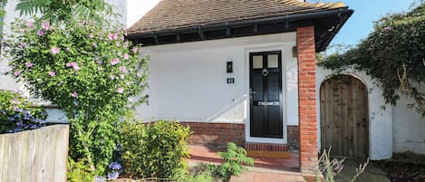 A residential property with a white exterior, a black door, and a brick entrance.
