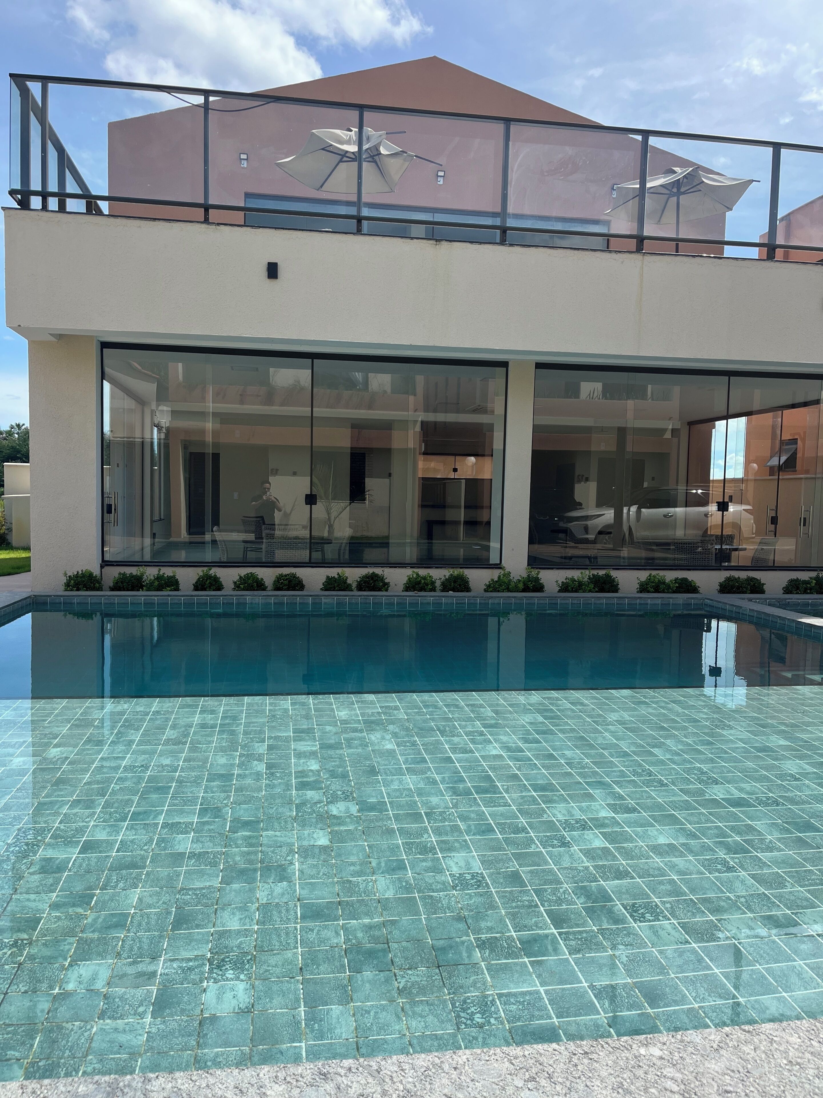 Una casa moderna amb piscina, grans finestres de vidre i zona exterior coberta.