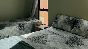 A hotel room with two beds, a window with curtains, an air conditioning unit, and a small table. - House 18 | Private Pool, Gourmet Area and 4 Suites - Near the City Center. (Barreirinhas)
