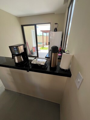 Ett litet kök med en kaffebryggare, en vattenkokare och en brödrost på bänkskivan.
