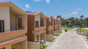 A row of modern hotel buildings with balconies, a paved walkway, and a pool area. - House 18 | Private Pool, Gourmet Area and 4 Suites - Near the City Center. (Barreirinhas)