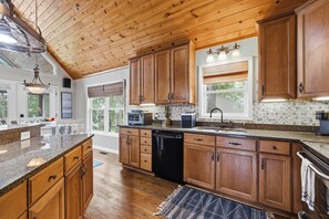 A spacious kitchen with wooden cabinets, a granite countertop, and a dishwasher. - Welcoming The Sinclair Hideaway (Sparta)