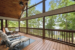 A covered deck with outdoor seating, large windows, and a view of a lake. - Welcoming The Sinclair Hideaway (Sparta)
