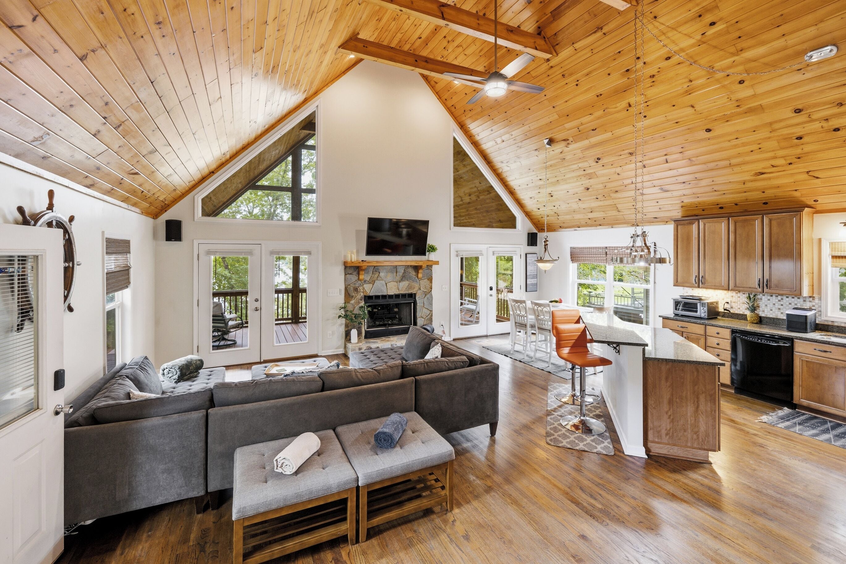 A spacious living area with a large sofa, a fireplace, and a kitchen with wooden cabinets and a bar area.