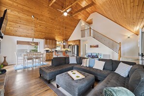 A spacious living room with a large sectional sofa, a dining area with a white table and chairs, and a kitchen in the background. - Welcoming The Sinclair Hideaway (Sparta)