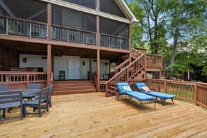 Une terrasse en bois dotée d’un espace couvert, de mobilier d’extérieur et d’un escalier menant à un niveau supérieur.